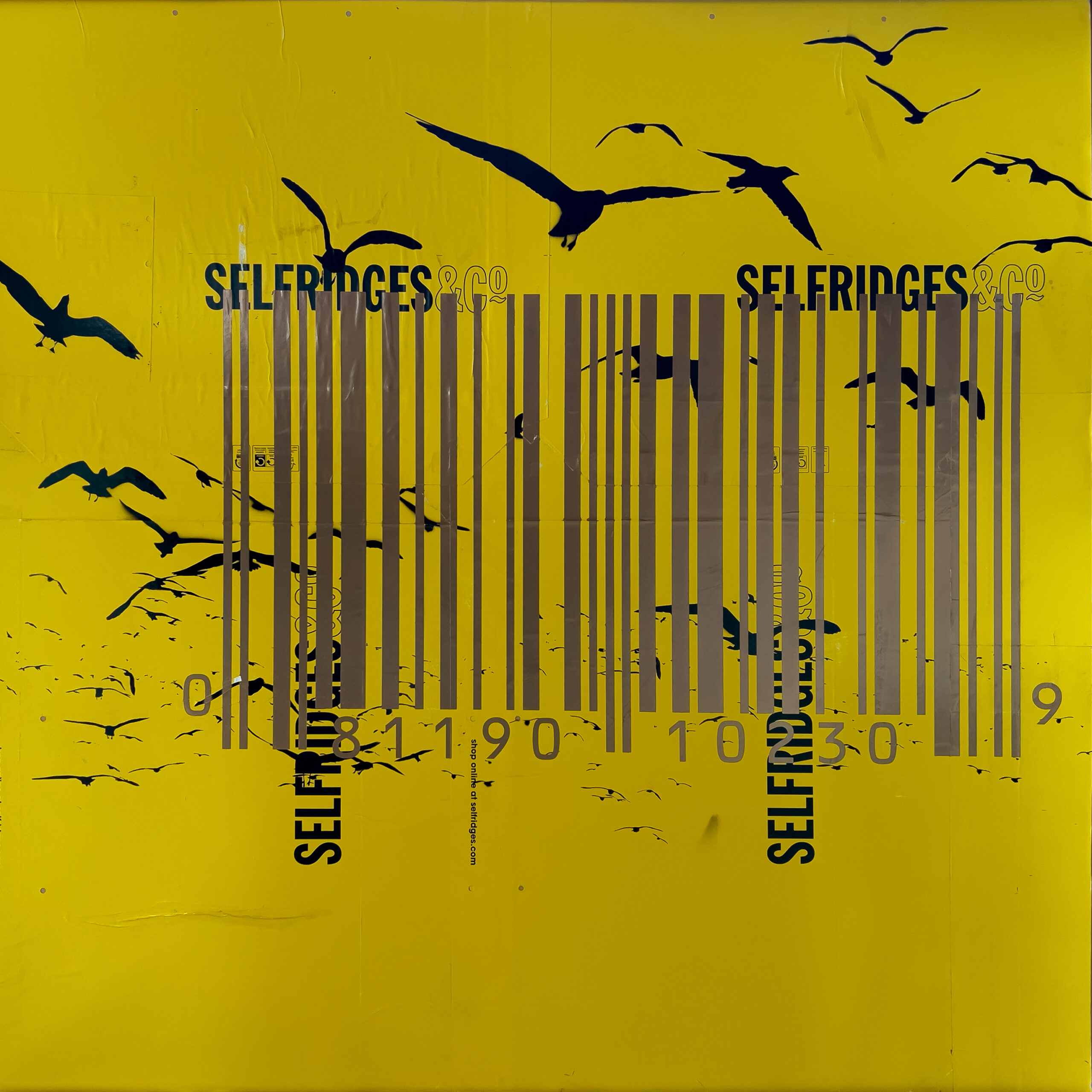 Yellow mixed-media painting with black silhouetted birds, repeated Selfridges branding and a large metallic gold barcode across the centre.